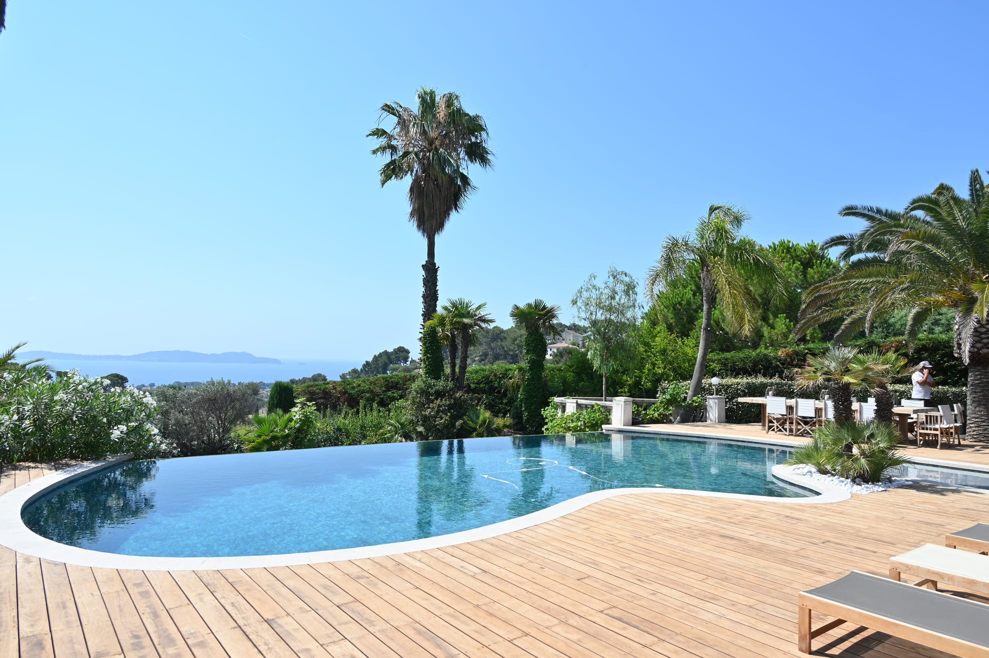 Une piscine à débordement avec une terrasse en bois